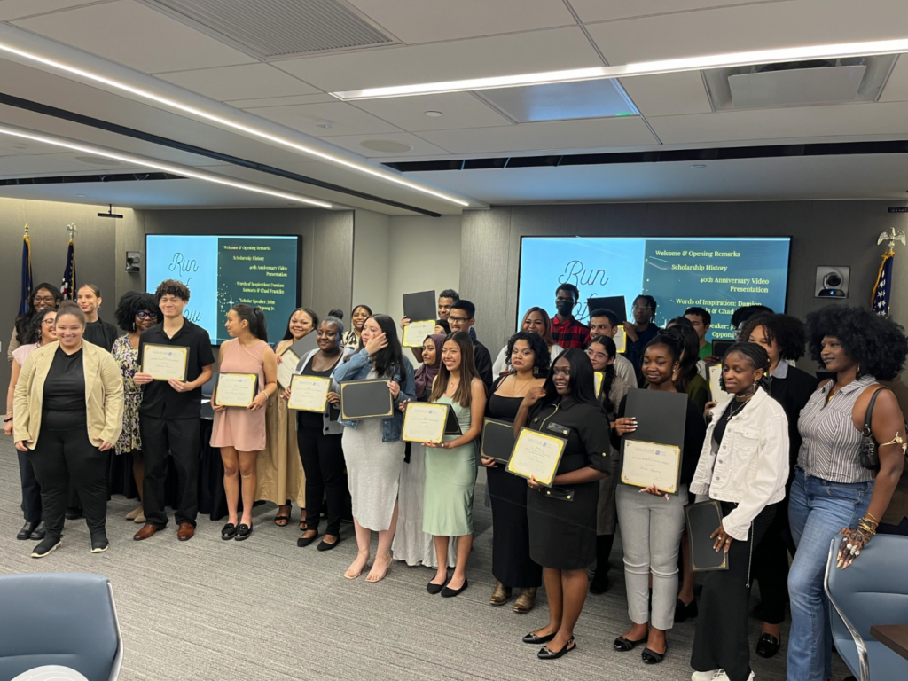 About 30 young people stand holding their scholarship certificates along with members of the Isaacs Center and Goddard staff