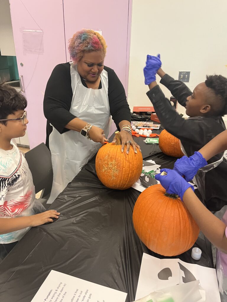 Woman and children carving pumpkins at a table