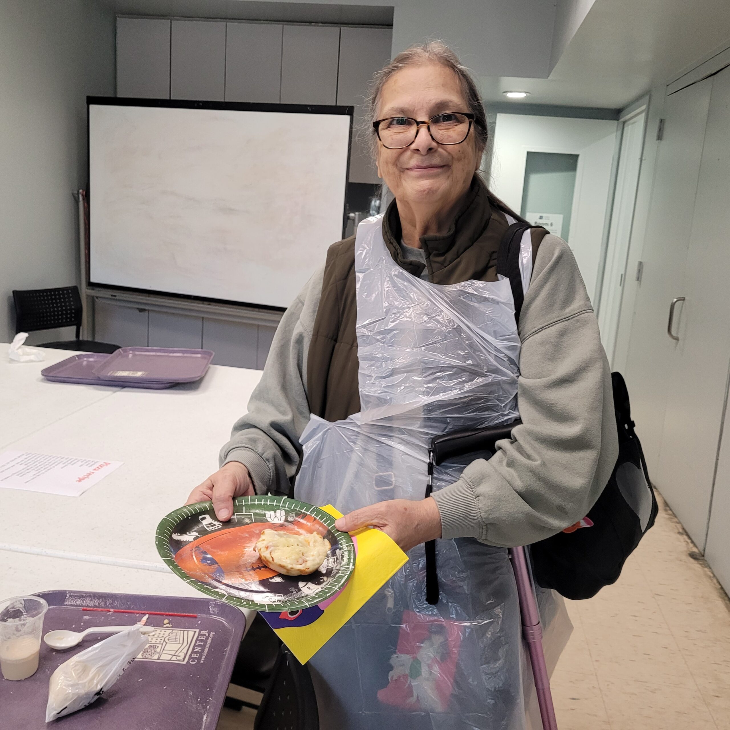 Woman proudly holding a mini pizza she cooked