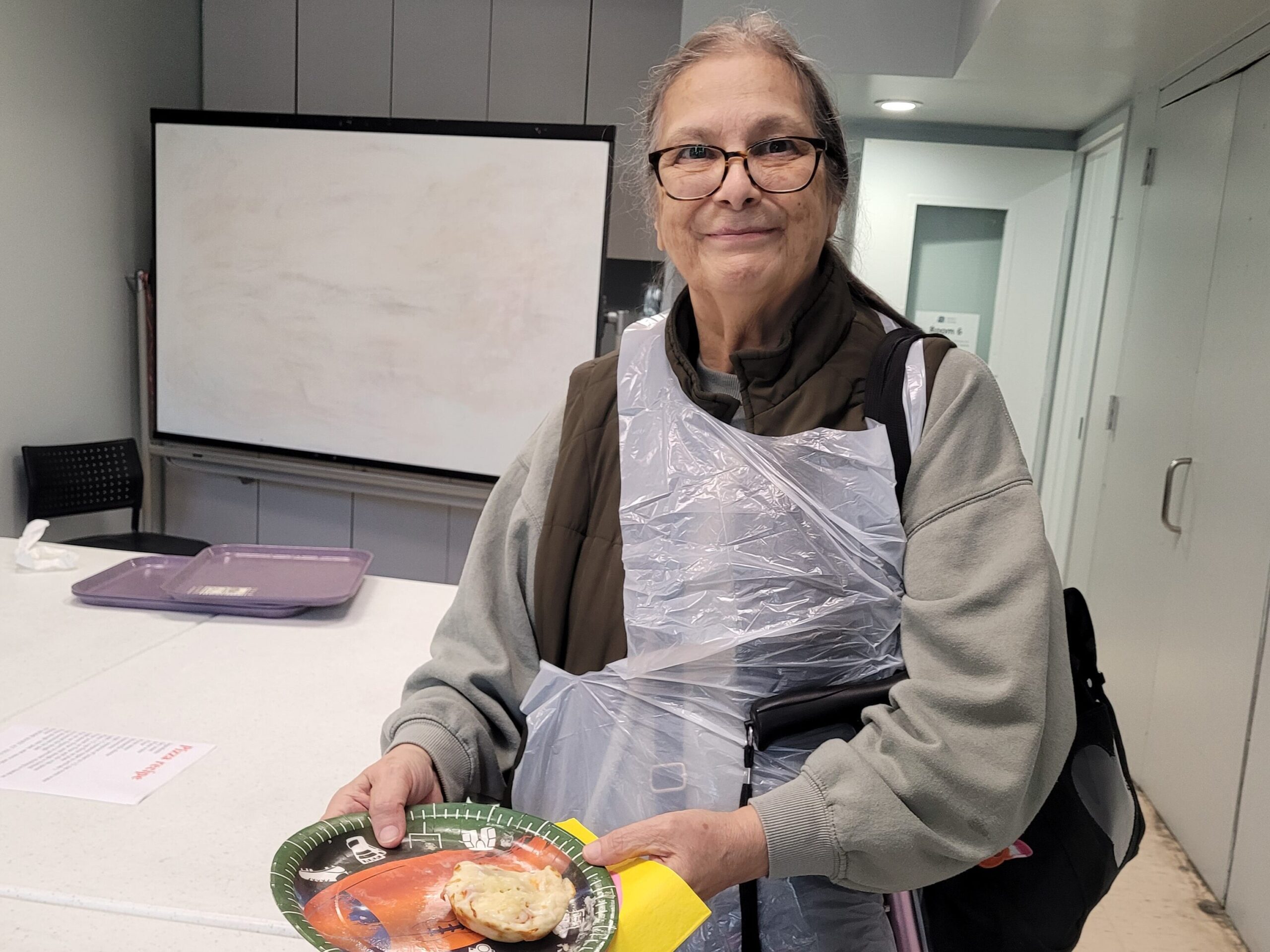 Woman proudly holding a mini pizza she cooked