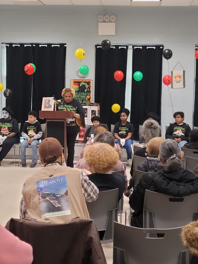 Saundra Coleman speaking at the event while the children sat down