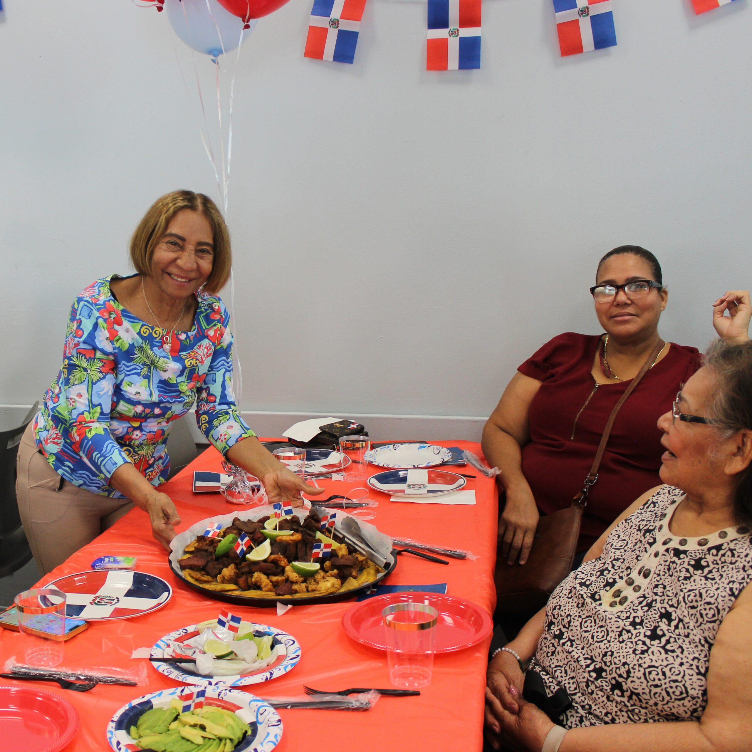 Older adult members at a table with Dominican food